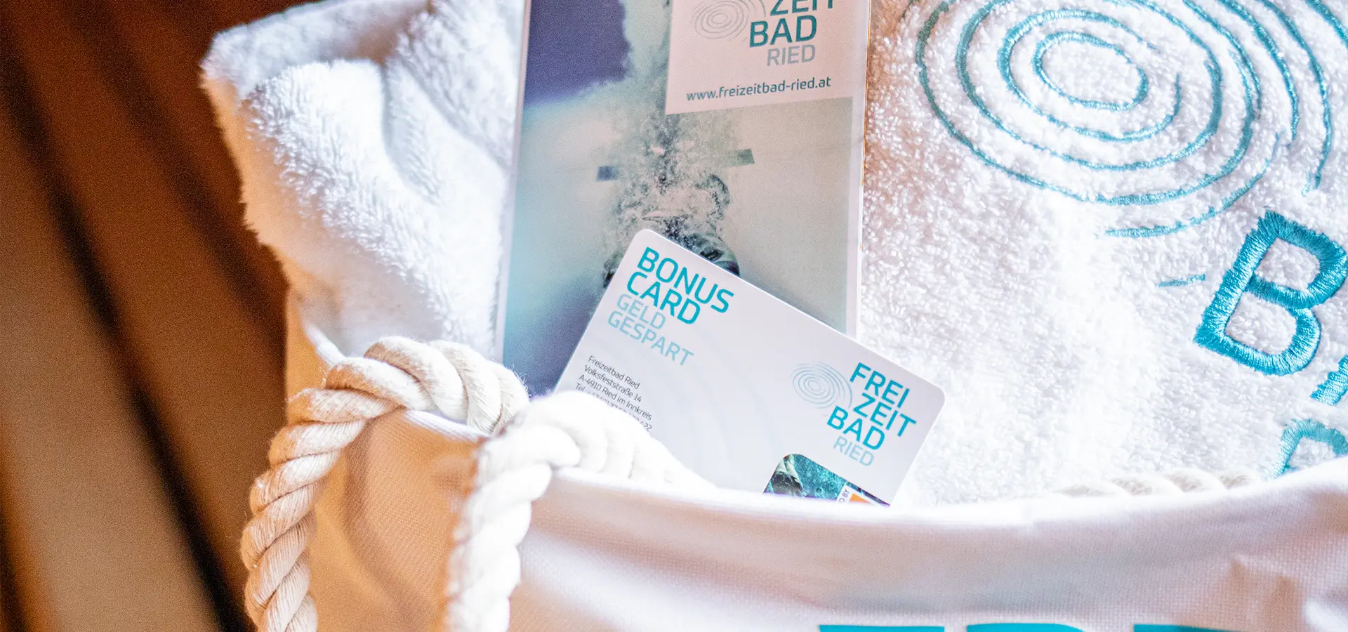 Detailaufnahme einer Badetasche mit Bonus Card, Handtuch und Flyer vom Freizeitbadried