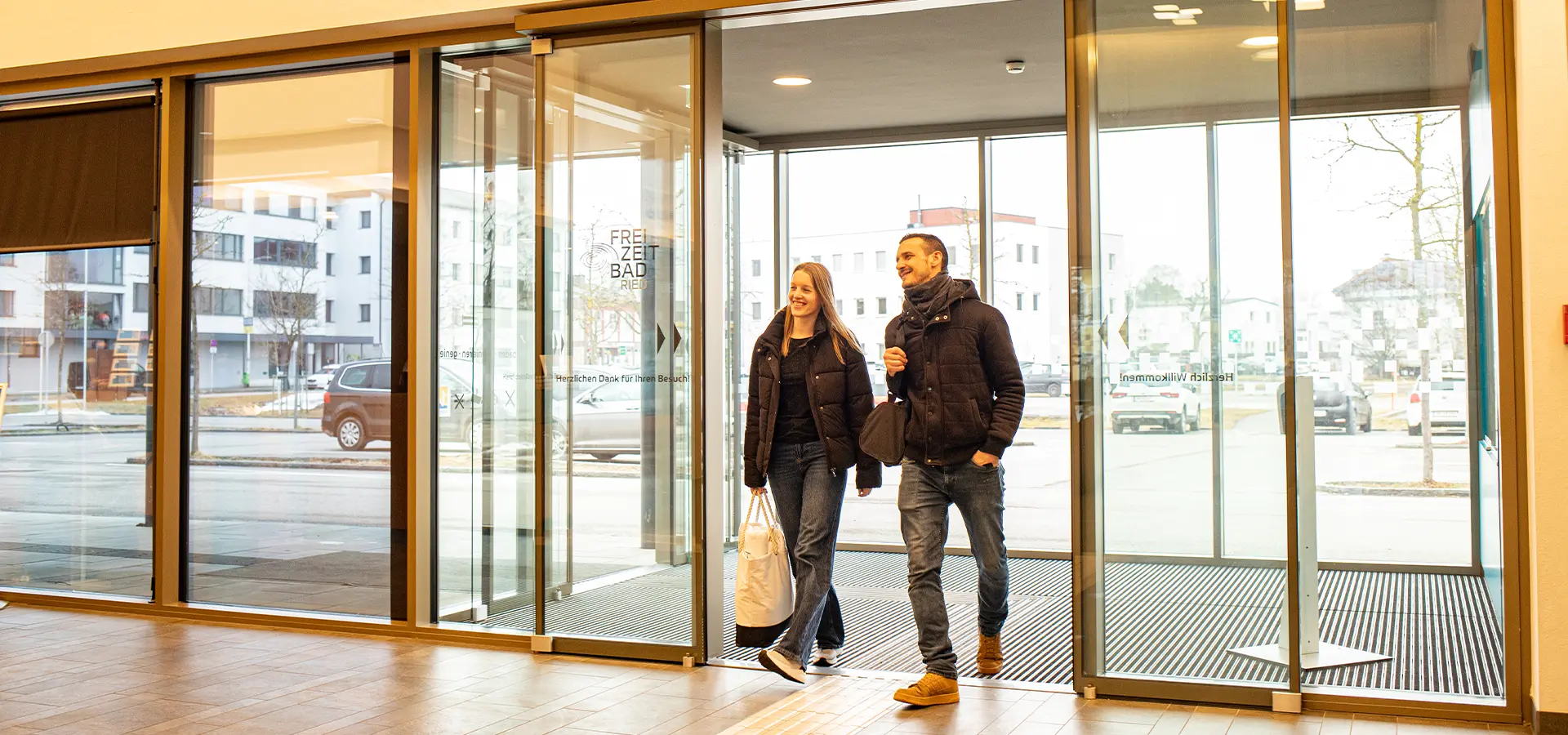 Eine Frau und ein Mann treten durch eine Schiebetür