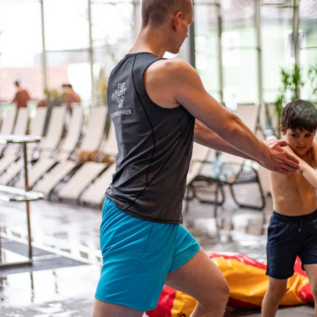 Schwimmtrainer macht Aufwärmübungen mit einem Jungen