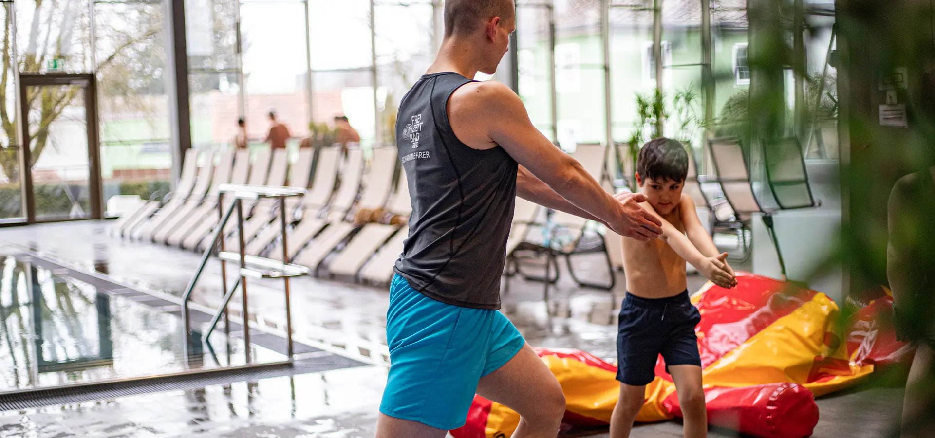Schwimmtrainer macht Aufwärmübungen mit einem Jungen