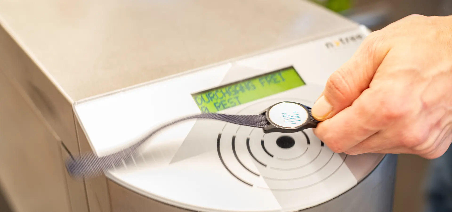 Person hält Chip-Band vor den Sensor mit dem Text: Durchgang frei