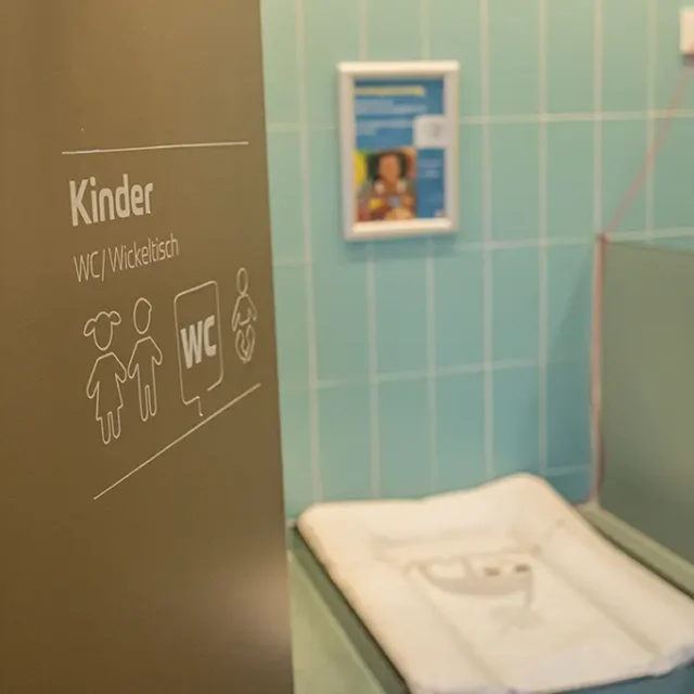 Tür mit Aufschrift geöffnet mit dem Blick auf einen Wickeltisch