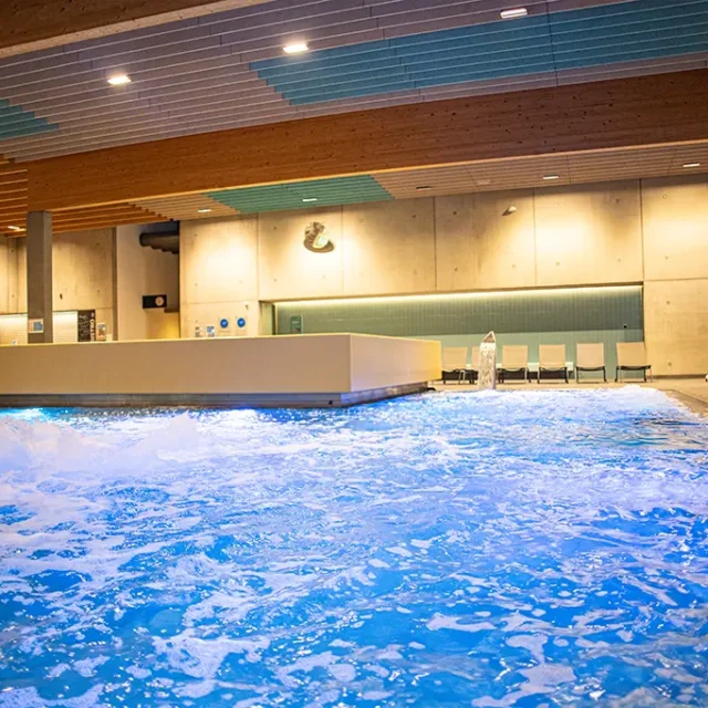 Kinderbecken am Abend beleuchtet. Es sind alle Attraktionen (Wassersprudel und Massagedüsen) eingeschaltet.