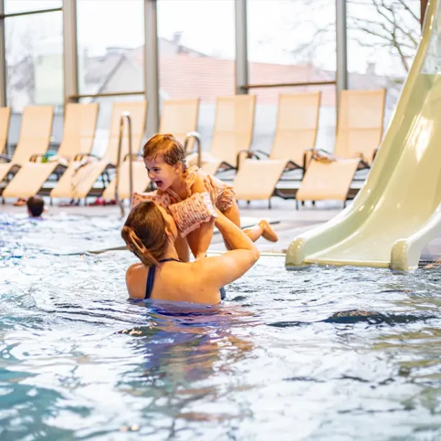 Kind rutscht bei der Kinderrutsche ins Familienbecken und wird von der Mama aufgefangen.