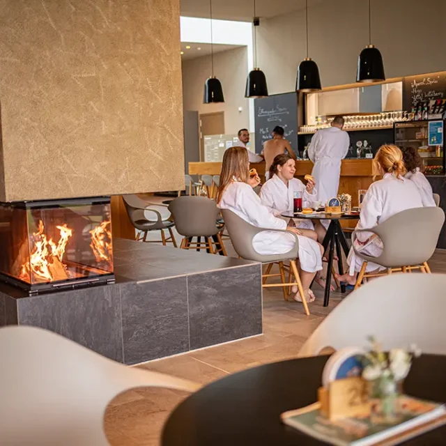 Sitzbereich mit Badegästen und Feuer im Kamin