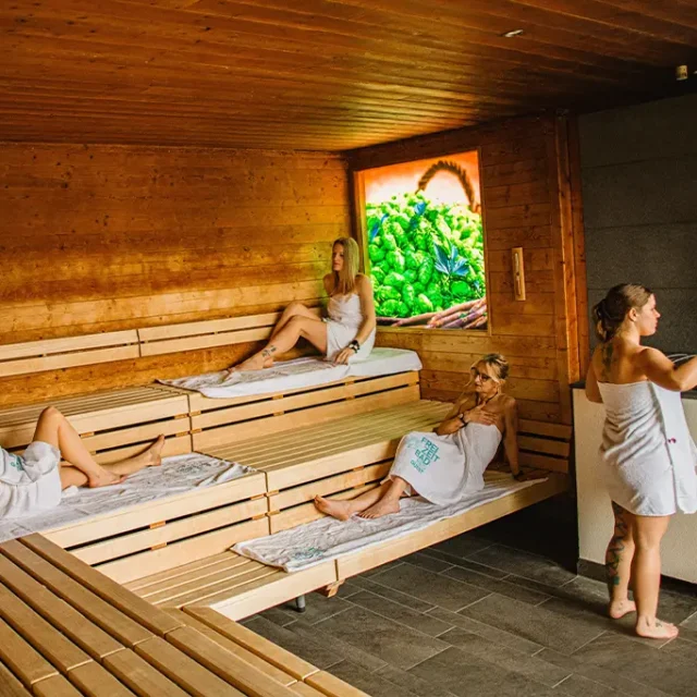 Dame macht einen Aufguss in der Hopfensauna mit anderen Gästen