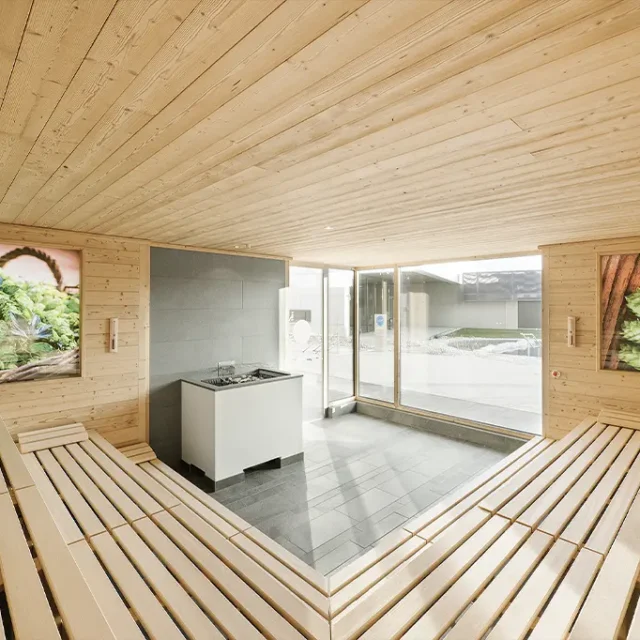 Innenansicht der Hopfensauna, mit hellem Holz der Sitzbänke und Hopfenbildern an der Wand