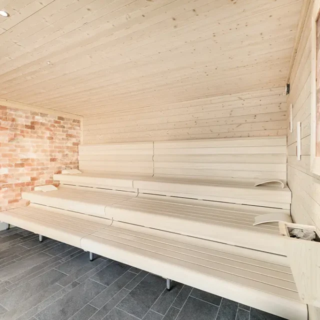 Innenansicht der Salzsauna, mit Salzstein an den Wänden und hellem Holz der Sitzbänke