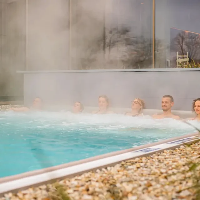 Badegäste sitzen auf den Sprudelliegen im beheizten Solebecken im Außenbereich