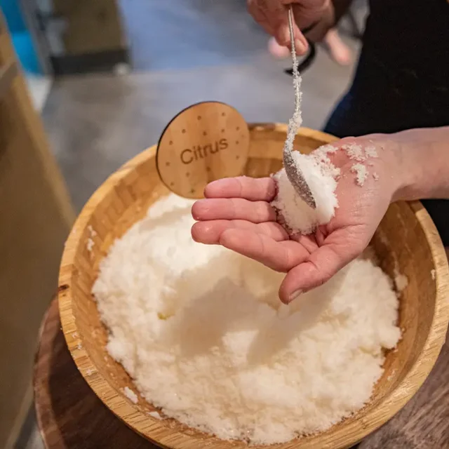 Salz wird aus einer Holzschüssel auf eine Hand gelöffelt