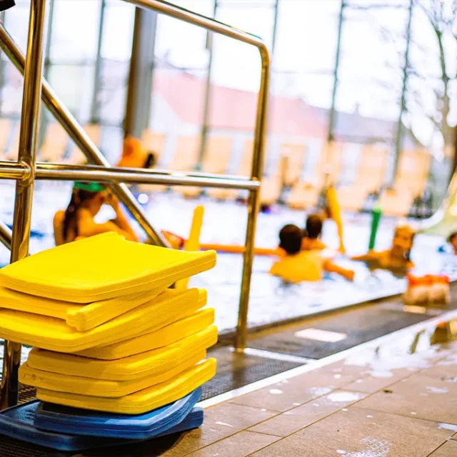 Schwimmhilfen am Beckenrand und Kinder im Wasser